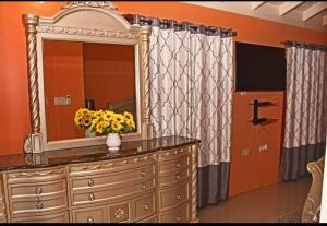 a dresser with a mirror and a vase with flowers on it at Irie Smart Villa 2 in Falmouth