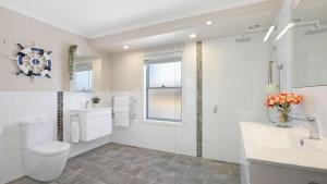 a white bathroom with a toilet and a sink at Coastal Bungalow in Callala Bay