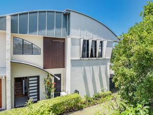 Casa blanca con puerta marrón y árboles en Beachside Escape on Cottonwood, en Casuarina