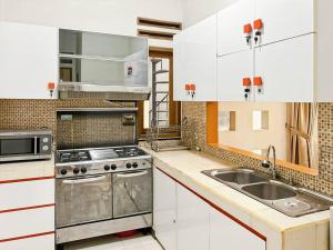 a white kitchen with a sink and a stove at Large Villa 3BR Dago Bandung by 2ndHome in Bandung +20 photos