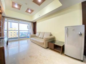 a living room with a couch and a refrigerator at Spacious and Modern 2BR at Braga City Walk Apartment By Travelio in Bandung