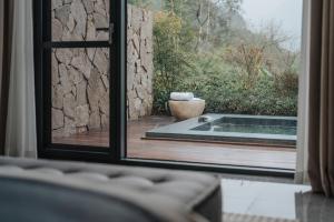 a window view of a patio with a tub outside at 峨眉山和院一溪清音酒店 in Emeishan City
