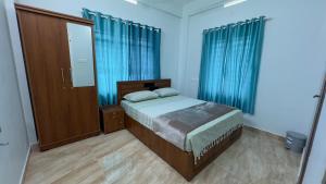 a bedroom with a bed with blue curtains and a mirror at The Karlyle Homestay in Vaduvanchal