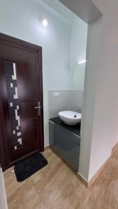 a bathroom with a sink and a wooden door at The Karlyle Homestay in Vaduvanchal