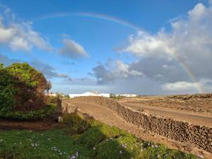 a rainbow in the sky over a dirt road at Casa Ina in El Roque, El Cotillo in Roque