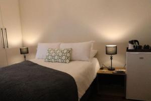 a bedroom with a bed with pillows and two lamps at Villa Des Roses in Paarl