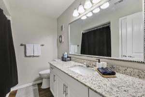 ein Badezimmer mit Waschbecken, Toilette und Spiegel in der Unterkunft Chic 1BD Retreat With Pool & Gym, Heart of Medical City Plano in Plano