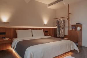 a bedroom with a large bed and a suit on a rack at 峨眉山和院一溪清音酒店 in Emeishan City