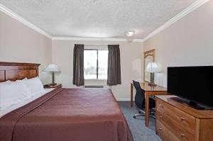 a hotel room with a bed and a desk and a television at Travelodge by Wyndham Pasadena Central in Pasadena