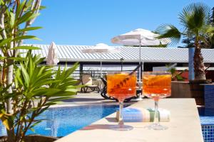 Zwei Weingläser stehen auf einem Tisch neben einem Pool. in der Unterkunft Hotel NOBEL Ultra All Inclusive - FREE Beach Access in Sonnenstrand