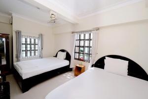a bedroom with two beds and two windows at Blue Sea 01 Hotel in Nha Trang