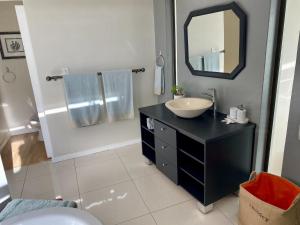 a bathroom with a black vanity with a sink and a mirror at Rose’s Place in Durbanville