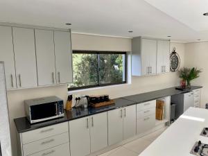 a kitchen with white cabinets and a microwave at Rose’s Place in Durbanville