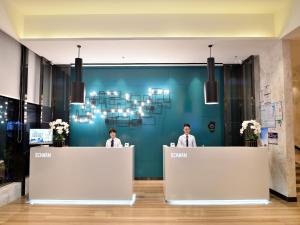 two people standing at the reception desks in a lobby at Echarm Hotel Kunming Baita Road Huidu International Store in Kunming