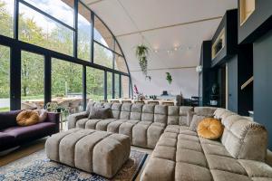 un soggiorno con un grande divano e una grande finestra di Bosresort Maanzicht a Noordwolde