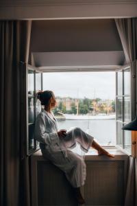a woman sitting on a window sill looking out at Hôtel Reisen in The Unbound Collection by Hyatt in Stockholm