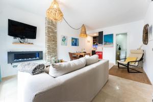 Una sala de estar con un sofá blanco y un televisor. en Mi Patio, Port Of Cabopino, en Marbella