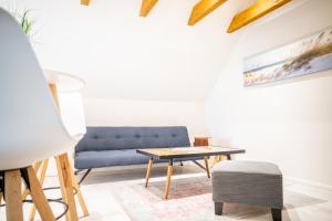ein Wohnzimmer mit einem blauen Sofa und einem Tisch in der Unterkunft Kapitänshaus - Boje in Born