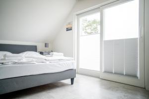 ein Schlafzimmer mit einem Bett und einem großen Fenster in der Unterkunft Kapitänshaus - Boje in Born
