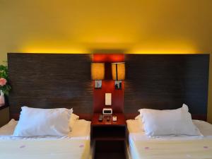 a hotel room with two beds and a head board at COZY Studio at Ming Garden Residence in Kota Kinabalu