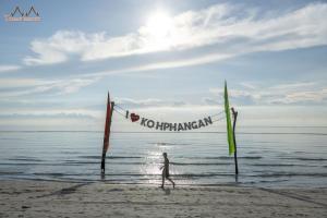 a man walking on the beach with a kite at Tommy Resort in Haad Rin