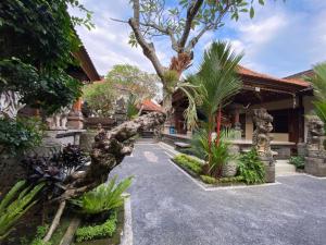 a house with a large tree in the driveway at Wirana Guest House in Ubud