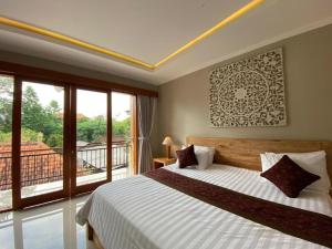 a bedroom with a large bed and a balcony at Wirana Guest House in Ubud