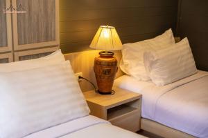 a bedroom with two beds and a lamp on a night stand at Tommy Resort in Haad Rin