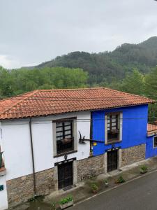 ein blau-weißes Gebäude mit einem Berg im Hintergrund in der Unterkunft Corias Casona junto al Narcea in Corias