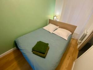 ein kleines Schlafzimmer mit einem Bett mit einem grünen Kissen in der Unterkunft Appartement entre plage de l'Ecluse et place du marché in Dinard