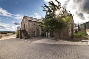 巴拉撒拉Grenaby Estates的一座古老的石头建筑,前面有一棵树