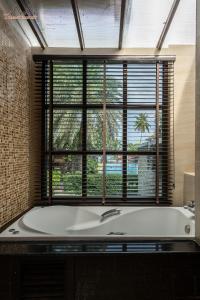 a bath tub in a bathroom with a large window at Tommy Resort in Haad Rin
