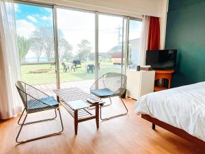 two chairs and a table in a bedroom with a bed at ゲストハウス星風 in Suo Oshima