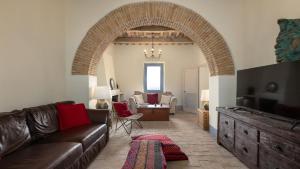 a living room with a brown leather couch and an archway at VILLA DEI ROSMARINI 8, Emma Villas in Orvieto