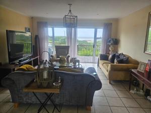 Una sala de estar con un sofá azul y un televisor. en Seabreeze Retreat Home, en Port Alfred