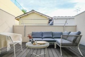 a patio with a couch and chairs on a balcony at UN-Villa in Tokyo
