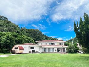 a house with a green yard and trees at ゲストハウス星風 in Suo Oshima