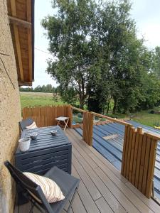 a wooden deck with chairs and a grill on it at Un Appart' à la campagne in Mordelles