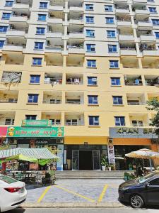 un grand immeuble jaune avec des voitures garées devant dans l'établissement Căn hộ 2 phòng ngủ view biển Mỹ Khê Đà Nẵng, à Đà Nẵng