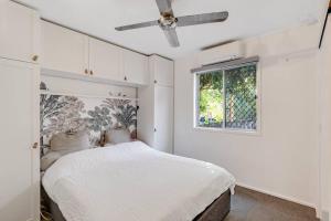 a white bedroom with a bed and a window at Beach Baby - Close to Cylinder Beach in Point Lookout