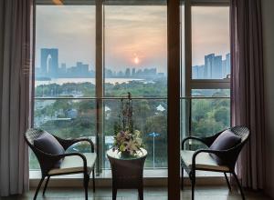 a room with two chairs and a table in front of a window at NOVOTEL Jinji Lake Suzhou SIP in Suzhou