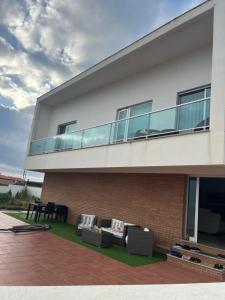 a building with a balcony with a couch and chairs at Haus am Strand in Póvoa de Varzim