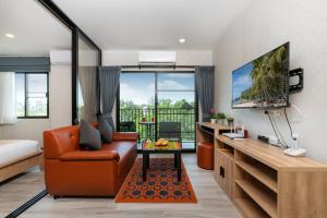 a living room with a couch and a tv at The Beach Residence by EHM in Nai Yang Beach