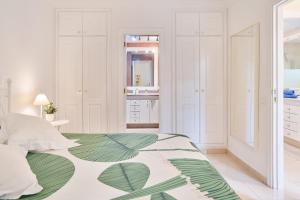 a white bedroom with a green and white bed at Terrazas del Duque Beach Apartment in Adeje +24 photos