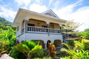 a white house with a balcony in a garden at Maison Ed-Elle in La Digue
