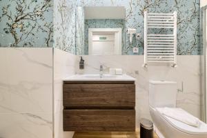 a bathroom with a sink and a toilet and a mirror at Deustown Apartamentos in Bilbao +94 photos