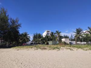 a beach with palm trees and a building in the background at Huy Hoàng Hotel Đà Nẵng in Da Nang