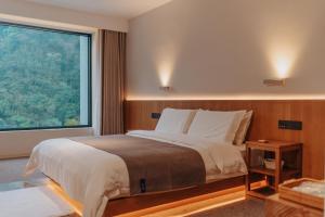 a bedroom with a large bed and a large window at 峨眉山和院一溪清音酒店 in Emeishan City