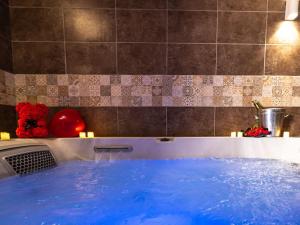 a hot tub with blue water in a bathroom at L'Évasion Sauna & Spa in Saint-Rambert-dʼAlbon