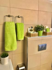 ein Bad mit grünen Handtüchern an der Wand in der Unterkunft Στην ΚΑΡΔΙΑ ΤΗΣ ΠΟΛΗΣ - in the HURT OF THE TOWN in Tríkala